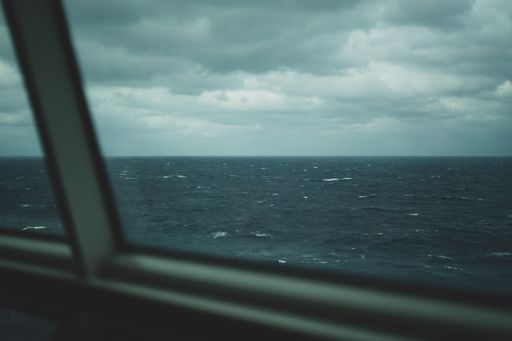 A beautiful shot of a stormy sea under a cloudy sky taken through a car window