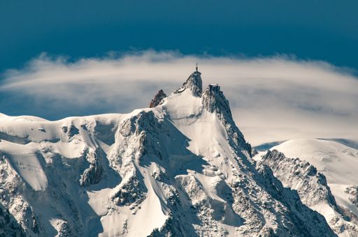 Close-up in winter with heavy snow on the ground and clooudy blue sky, Aiguille du Midi, Mont Blanc massif