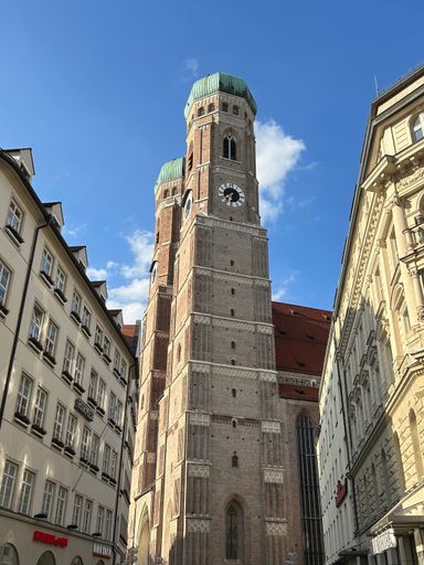 A closeup shot of a clock tower located in a city, with two buildings in the background