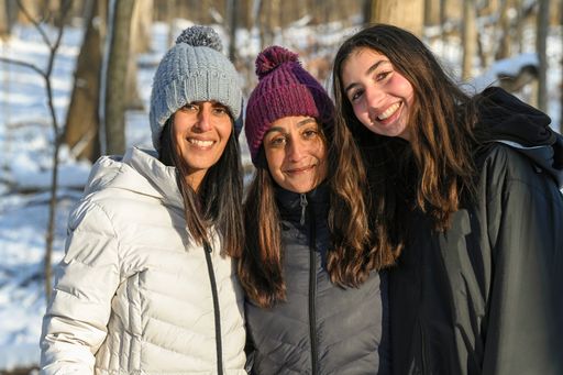 Three women from same family on a winter day with snow and woods in the background.