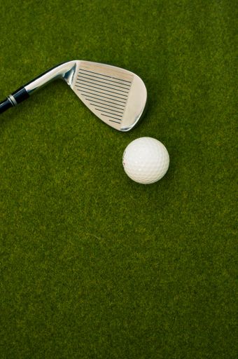 A vertical shot of a golf club and a ball on the grass with a copy space