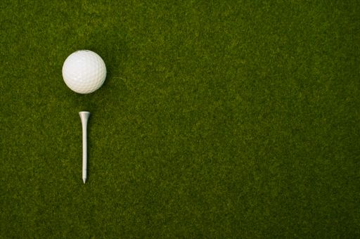 A top view of a golf ball and a tee on the grass with a copy space