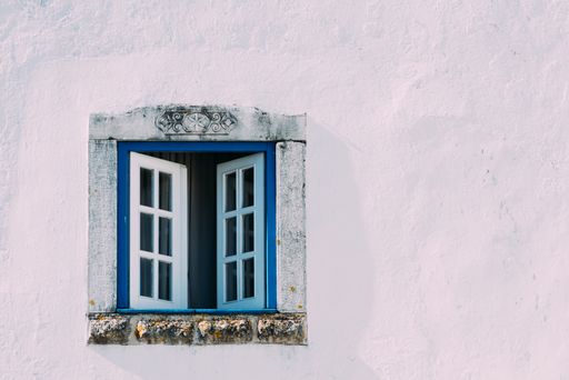 A pink building with white-blue beautiful window with ornaments in Obidos, Portugal