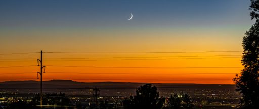 A moon rising over a misty mountain landscape in this tranquil nighttime scenery