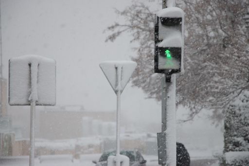 A street covered in snow during heavy misty weather in the city with a green streetlight