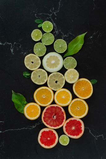A variety of colorful fruits, including apples, oranges, grapes, and bananas, arranged in a tower-like structure on a white surface