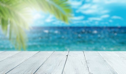 A white plank table top on blurred ocean background