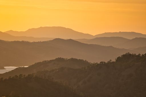 A landscape of hill silhouettes covered in forests during a beautiful golden sunset in the evening