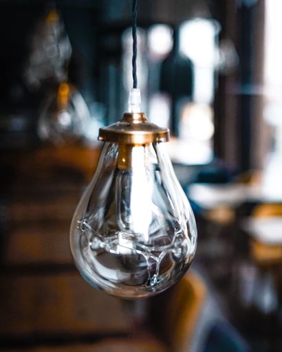 A vertical shot of a decorative lightbulb hanging from the ceiling in a cafe