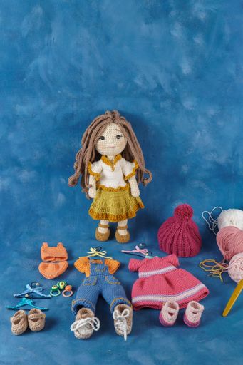 A cute amigurumi doll handmade on a blue background with clothes and accessories