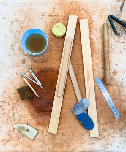 A canvas covered table with various pottery tools for making ceramics