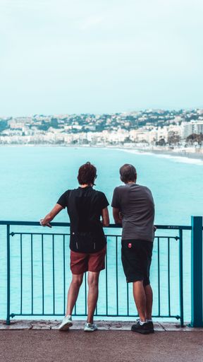 Two people overlooking the sea standing at a railing in Nice, France
