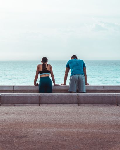 Two people overlooking the sea standing at a railing in Nice, France