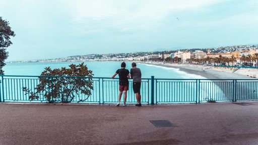 Two people overlooking the sea standing at a railing in Nice, France