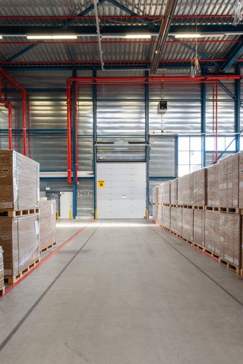 A warehouse with a loading door and pallets with boxes