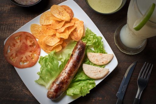 A top view of a plate with chorizo, arepa, and salad