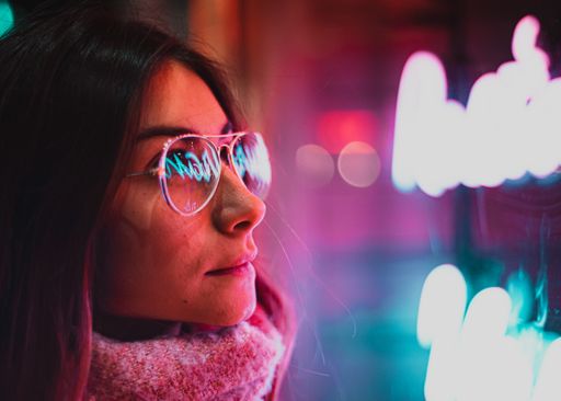 Reflection of neon lights on a girl's glasses