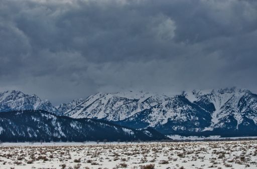 A snowy field on background of mountain rocks covered by dense clouds in Grand Teton National Park