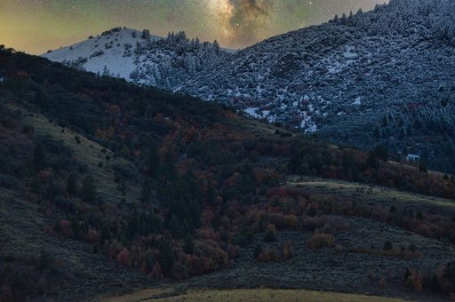 A superb shot of colorful Milky Way glowing in the sky seen through snow-covered mountains