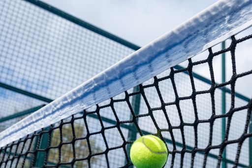ball hitting the net of a paddle tennis court, racquet sports concept