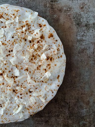 A vertical high angle shot of a delicious pie with creamy icings on a wooden surface