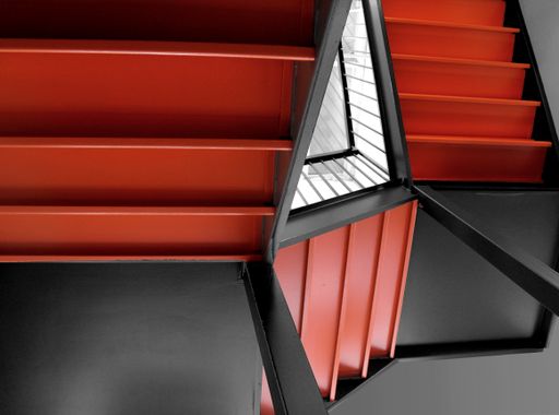 The orange staircases of a building next to a mirror