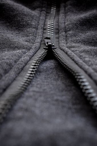 A vertical shot of the zipper of a wool texture sweater