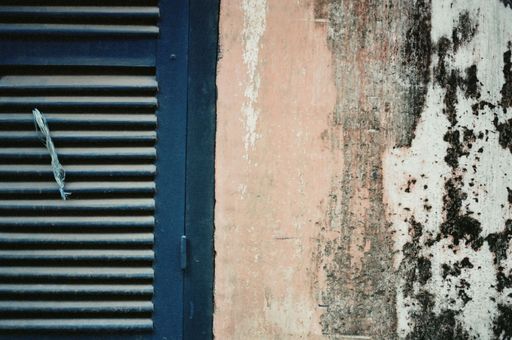 A close-up view of a weathered wooden door with a gray-colored wall behind it