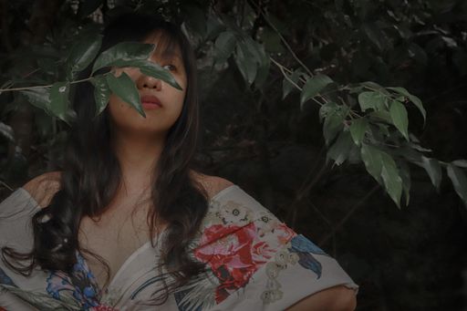 A closeup shot of an attractive Asian female in floral dress among the vegetation