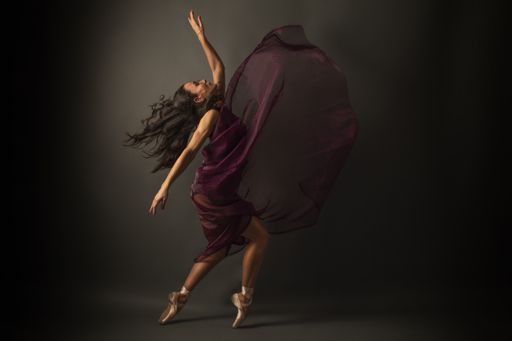 A graceful ballerina dancing on a gray studio background