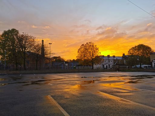 A stunning shot of a sunrise over an empty town parking lot, bathed in golden light