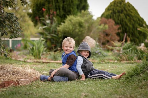 A closeup shot of two white Caucasian young kids sitting on grass