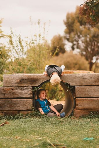 A vertical shot of two white Caucasian young kids playing together in a park