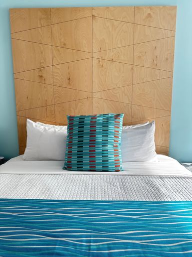 A cozy bed with a white and blue pillow on bed