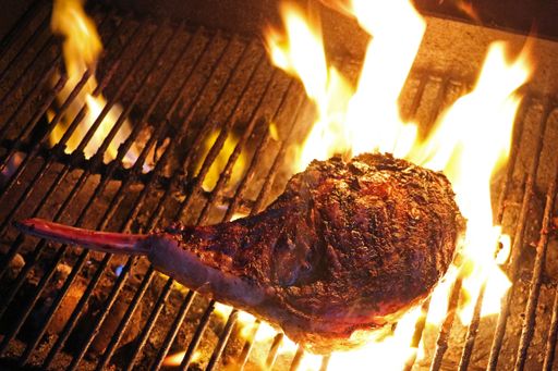 A closeup of tomahawk rib eye on a flaming grill
