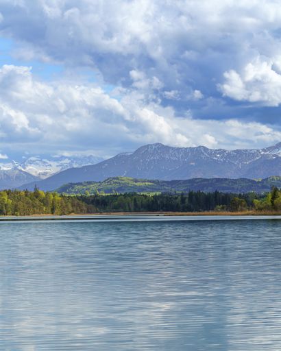 A vertical shot of a beautiful blue lake in spring on a cloudy sky background