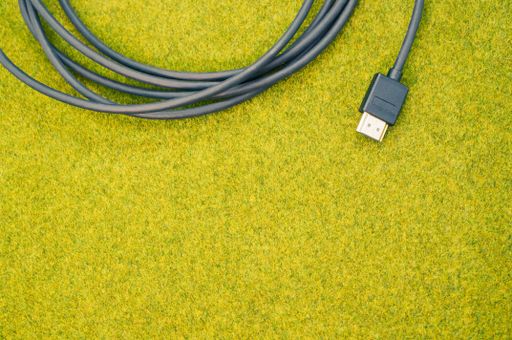 A top view shot of a rolled black cable on a green grass surface