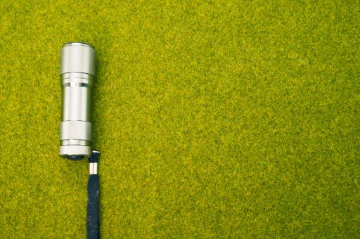 A top view shot of a flashlight on a green grass surface