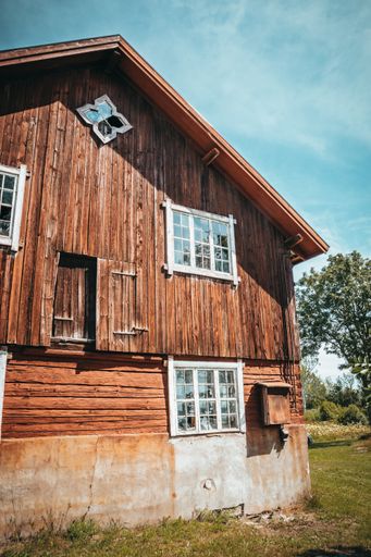 A low angle shot of a big wooden house with outside glass windows with a clear blue sky in the background