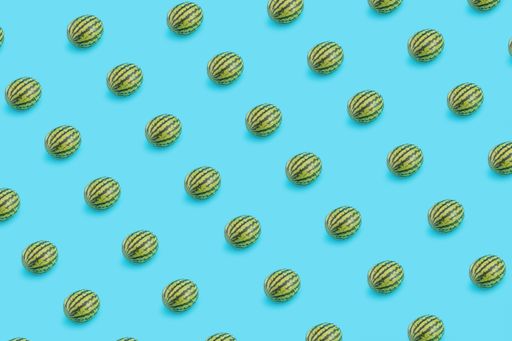 A closeup shot of multiple watermelons on a pastel blue background