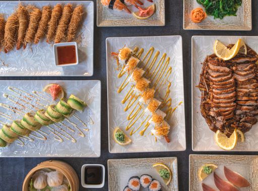 A top view of an assortment of Asian dishes of fish and sushi