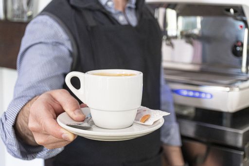 A man in the kitchen pouring a mug of hot filtered coffee from a glass pot