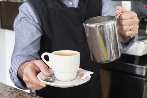 A man in the kitchen pouring a mug of hot filtered coffee from a glass pot