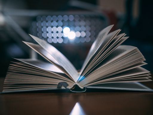An opened book with many pages and blurred light in the background