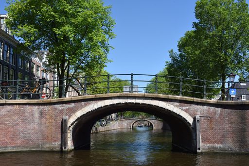 A scenic view of a bridge leading over a river surrounded by tall buildings in the background