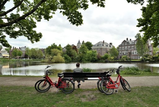 A leisurely scene of a person enjoying the outdoors, sitting on a park bench surrounded by bicycles