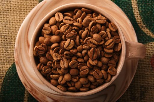 A ceramic mug filled to the brim with freshly roasted coffee beans.