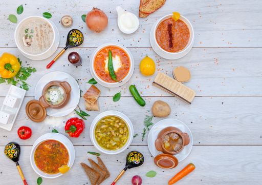 A flat lay composition of hot peppers with spicy sauces and mushroom soup on a wooden table