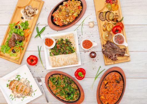 A flat lay of restaurant menu on wooden table - roasted beef with spicy soups and sauces around