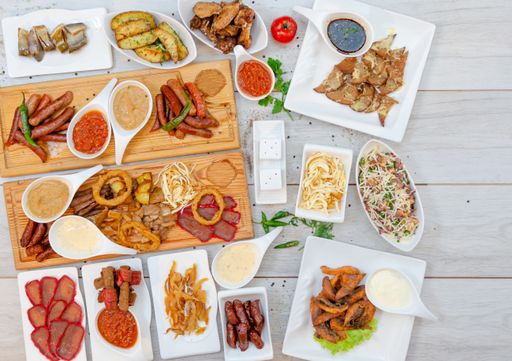 A top view of a wooden table filled with delicious spicy dishes consisting of meat, potatoes and salads